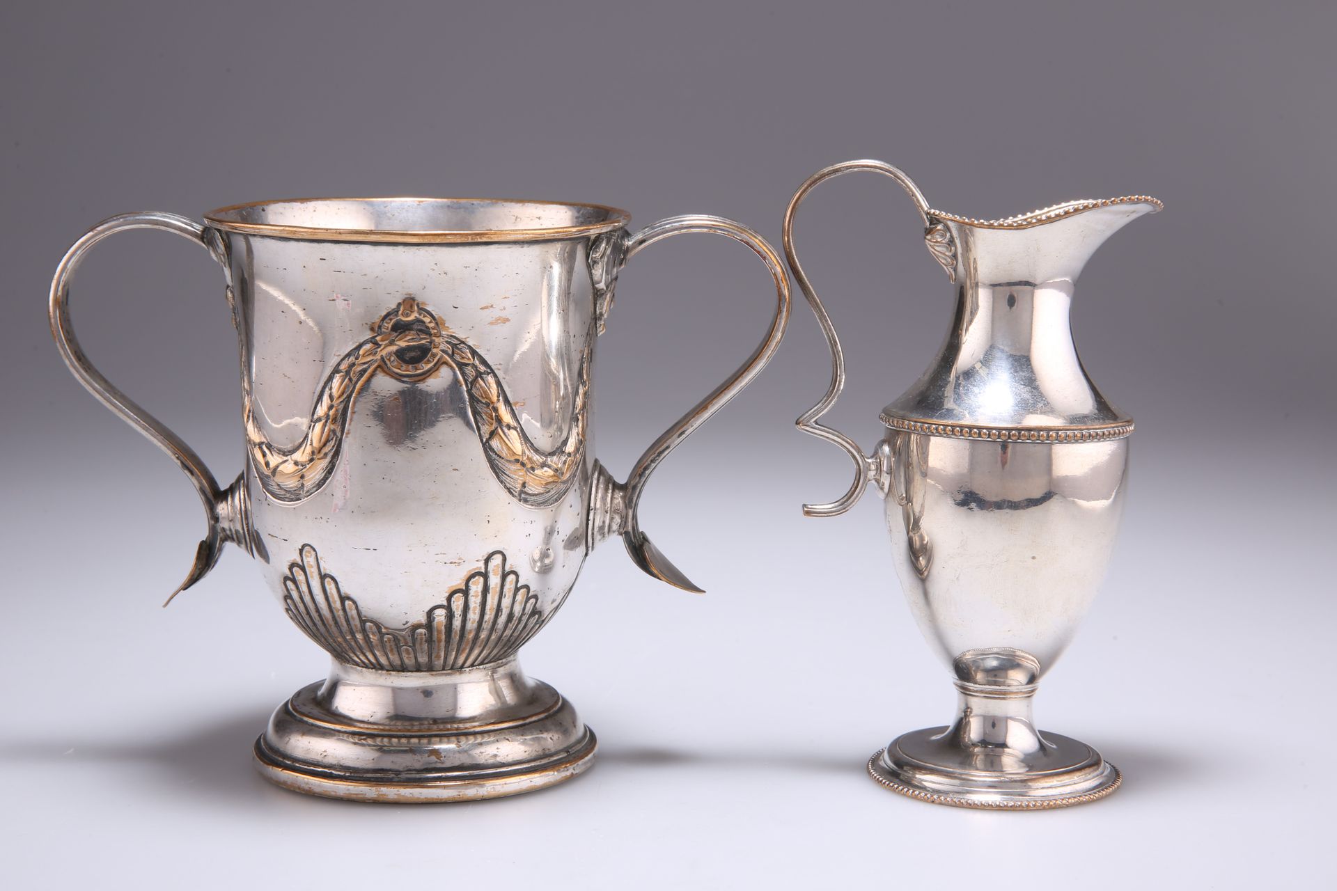 Null 一件旧谢菲尔德牌双柄杯，约1785年，带翻边把手，杯身装饰有花环，高12.5厘米；连同一件旧谢菲尔德牌奶油杯，带珠边，高13.5厘米。(2)80120&hellip;