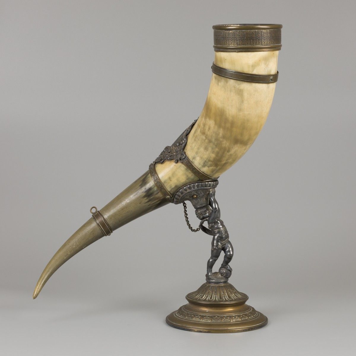 A drinking horn made of an ox horn, carried by a putto, ca. 1920. Stima: € 70 - &hellip;