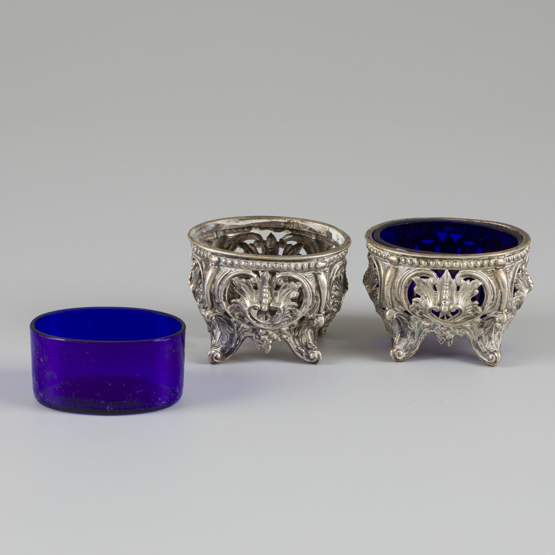 2-piece set of salt cellars silver. 椭圆形，有丰富的装饰和部分镂空。还带有原来的蓝色玻璃嵌件。19世纪，标记。Z - 有磨损&hellip;