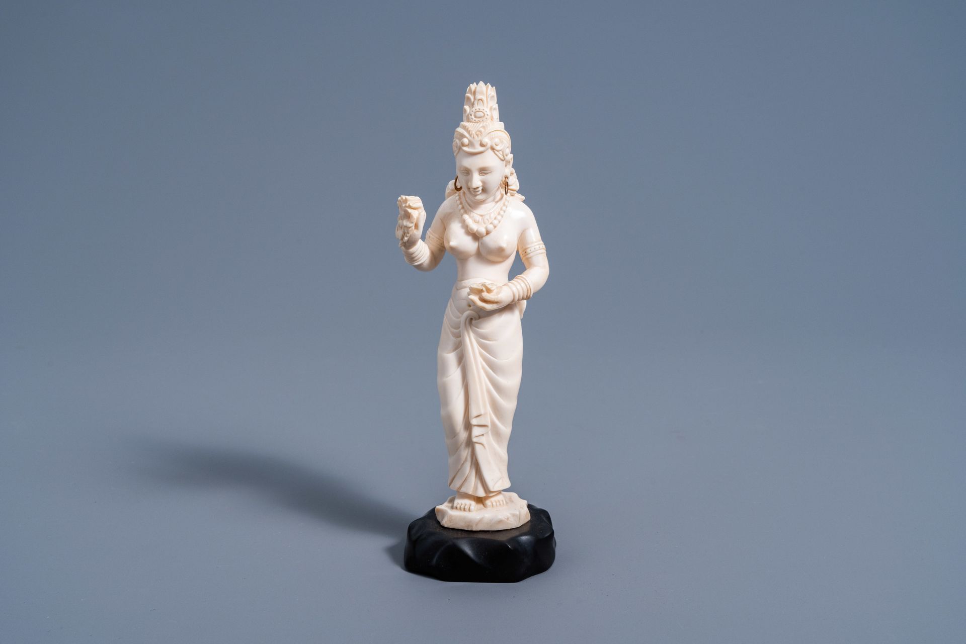 An Indian carved ivory figure of a goddess holding flowers in her hands, ca. 190&hellip;