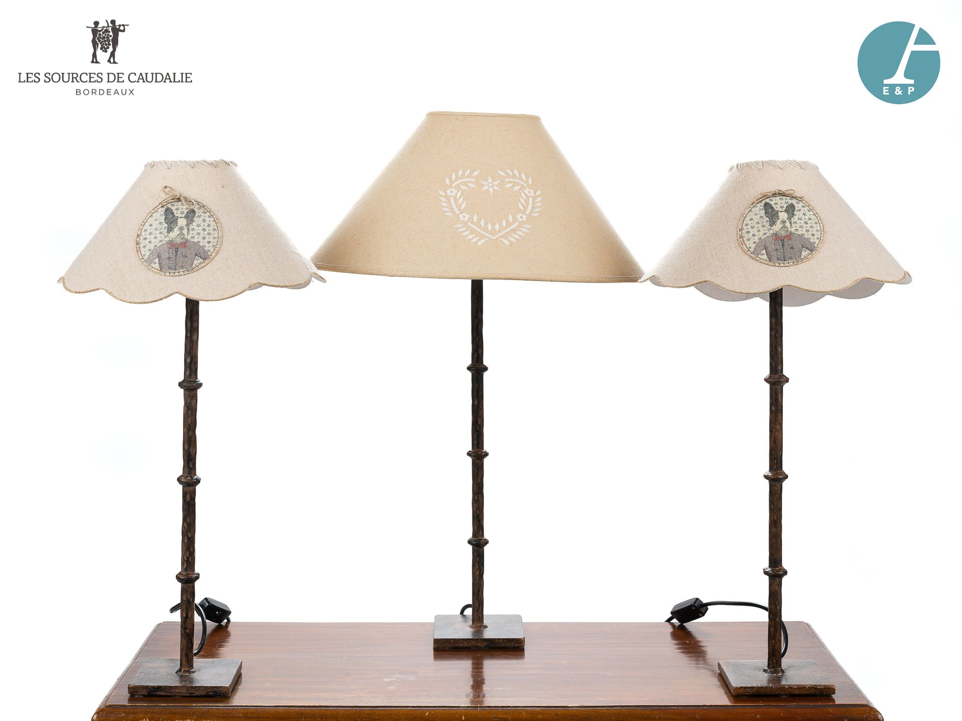 Null 从4号房间 "Les Douelles "出发

一套三盏灯，包括一对锻铁灯，环形脚，米色灯罩上有狗的徽章。

高：63.2厘米

和一盏锻铁灯，环形&hellip;