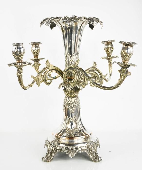 Null 一个令人印象深刻的19世纪的镀银中心器皿，有四个卷轴状的可移动的树枝，提高了郁金香形式的烛台，中央的喇叭形的叶状烛台提高在一个有四个面罩压花脚的底座上&hellip;