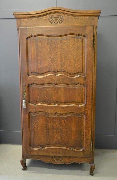 Null A French single door oak armoire, with shaped and carved top, above a panel&hellip;