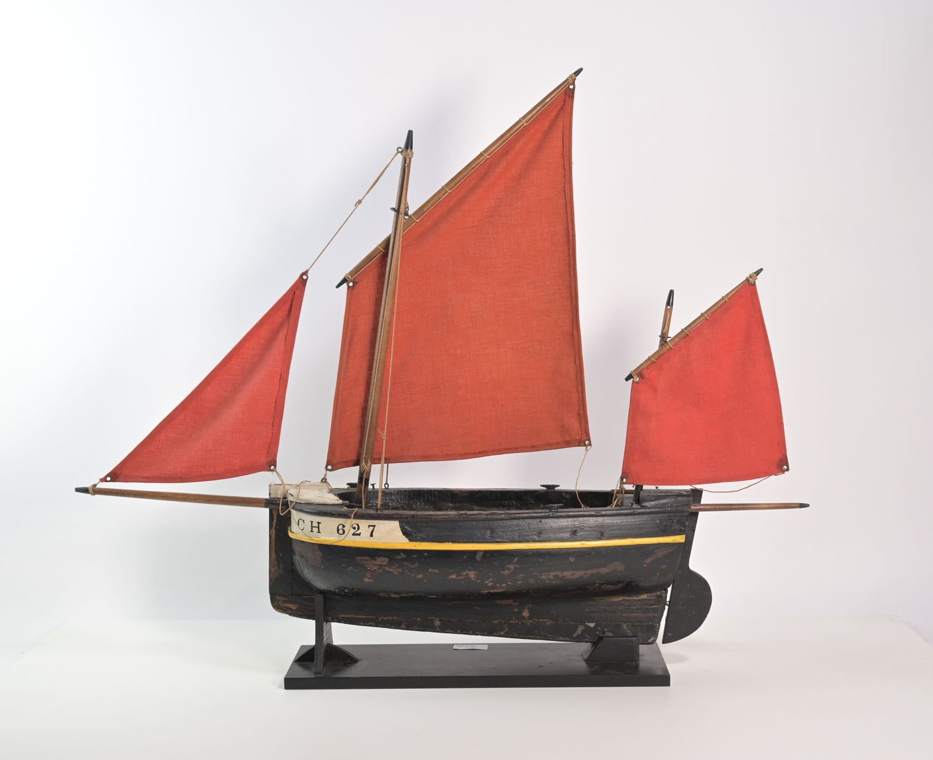 Null 来自瑟堡的渔船模型。黑漆木质的一体式船体，注册号为CH 627。帆为红色织物。在它的展示架上。 长度：80厘米。高度：66厘米