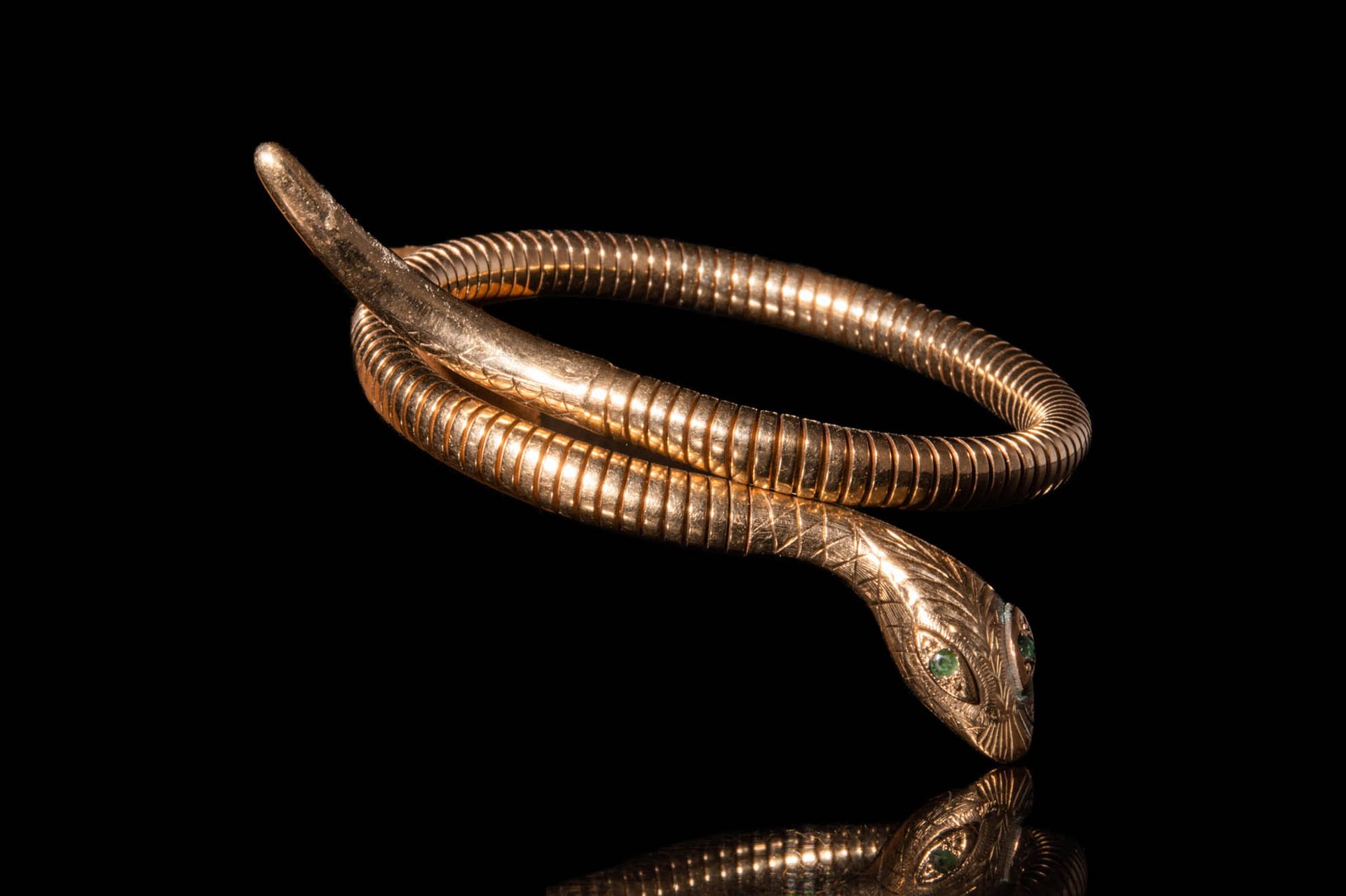 REVIVAL EGYPTIAN SNAKE SHAPED BRACELET .
埃及复兴时期的金手镯，蛇形镯身缠绕在一起。头部饰有鳞片，眼睛镶嵌祖母绿。 
尺&hellip;