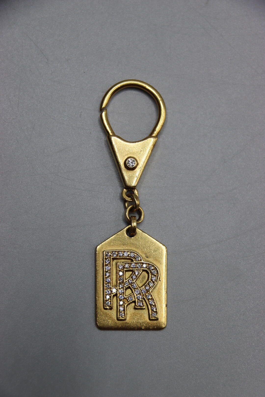 Null 黄金钥匙圈，装饰有小型明亮式切割钻石。吊坠上有双R（劳斯莱斯）的装饰。毛重：19.7克。