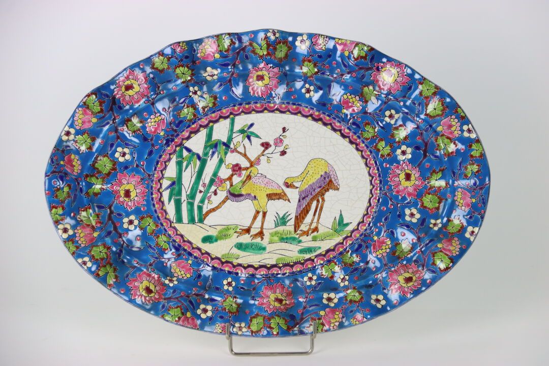 Null 在龙威的味道中。重要的有裂纹的陶瓷盘，多裂纹的边缘，蓝底的花卉珐琅，中央的圆盘上有两只鹳的风格化的装饰。背面盖有印章。长度：48厘米。