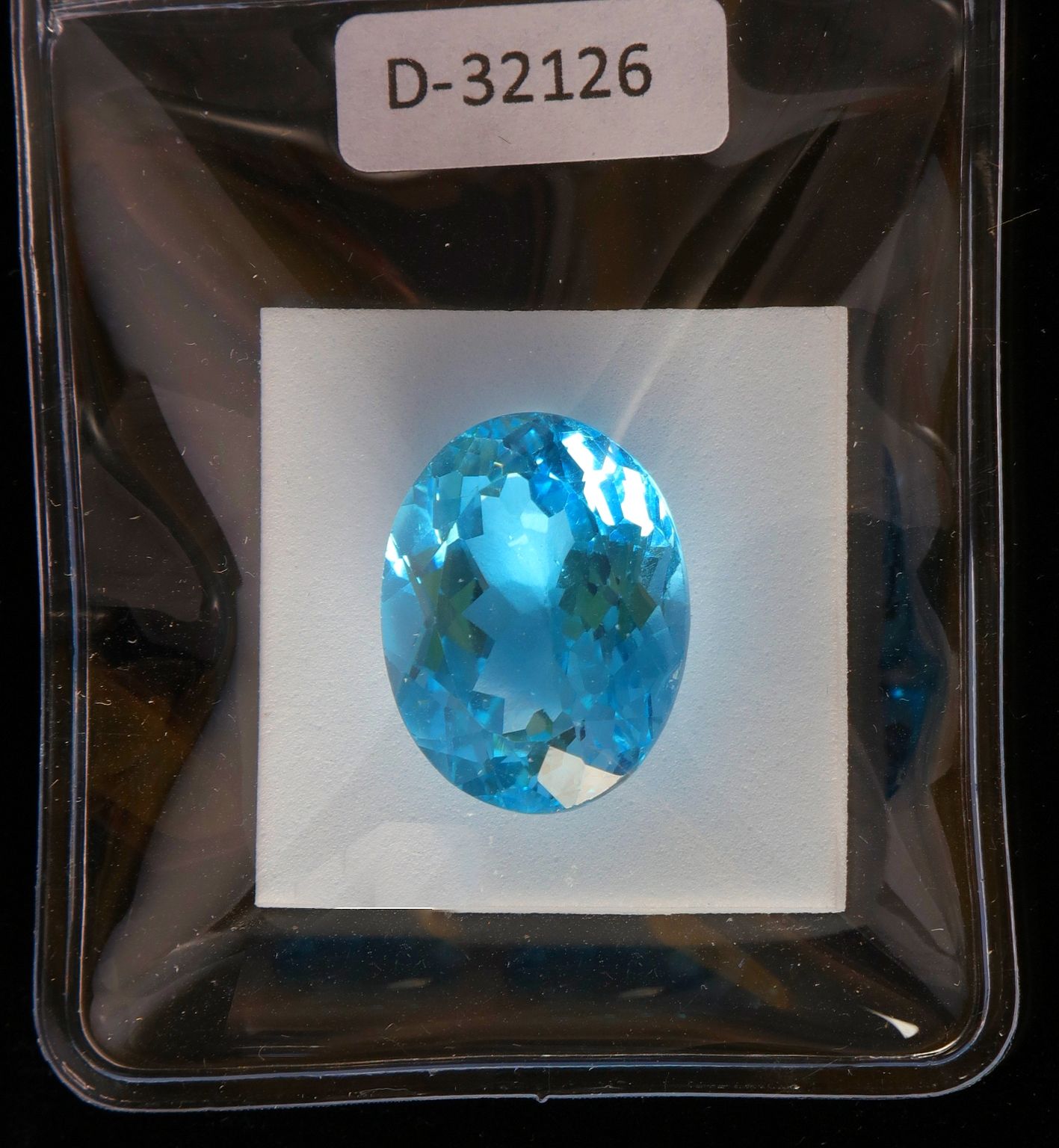 Null 印章下的蓝色黄玉。重量：24.73克拉，19.81x15.41x10.63毫米。证书编号：D-32126。
