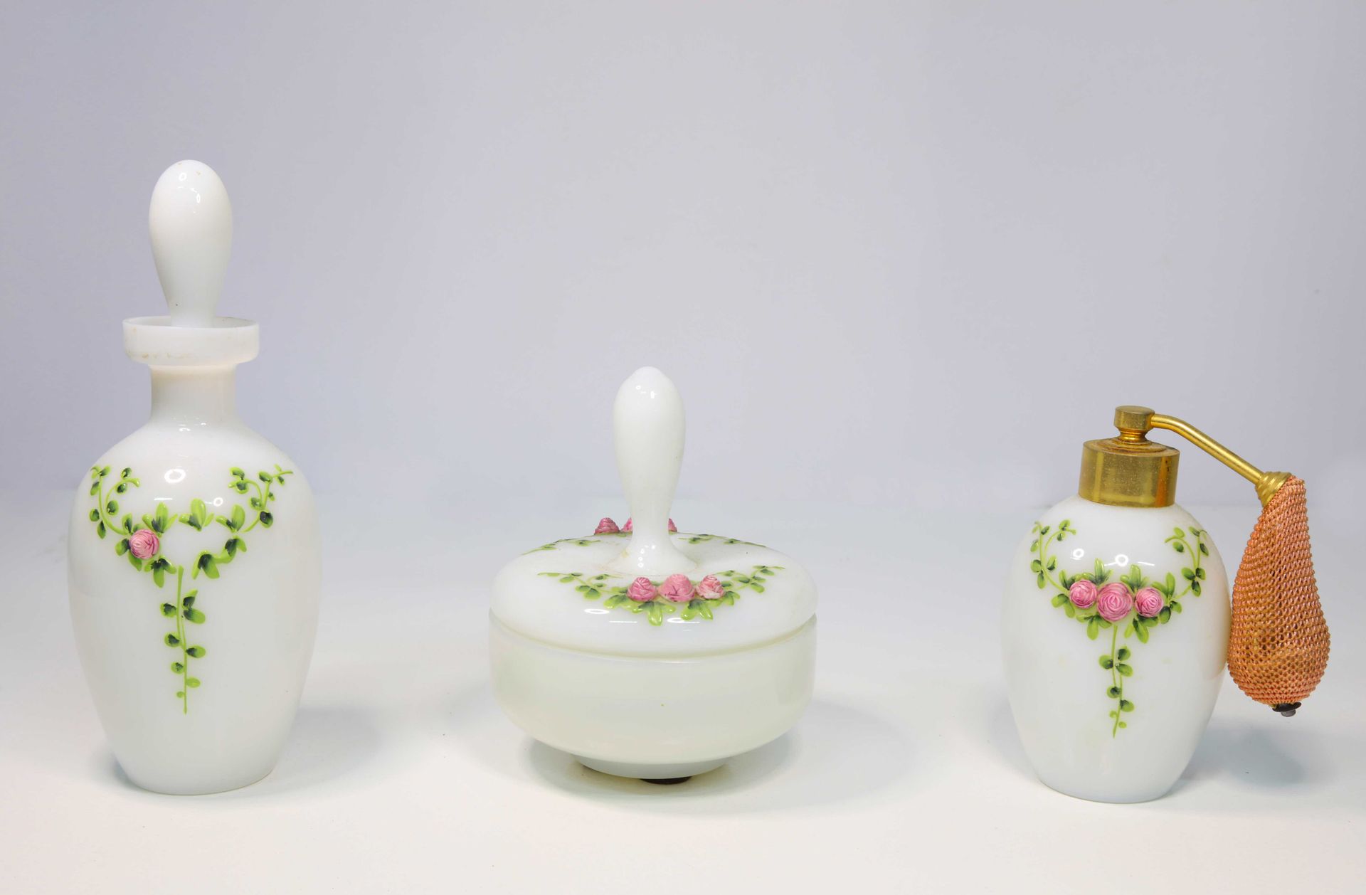 Null 三个白色乳白色的洗漱用品瓶，上面有浮雕的玫瑰花装饰。