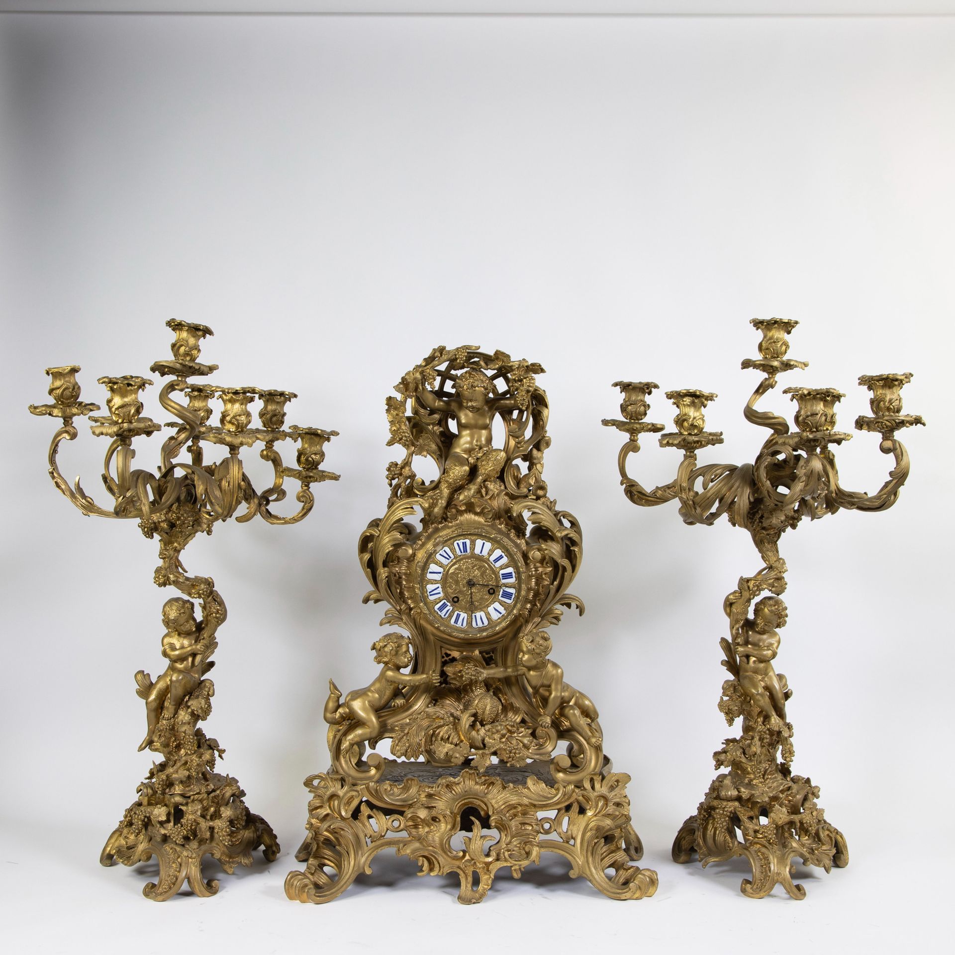 Null 一个令人印象深刻的由三部分组成的路易十五镀金时钟，来自Vincenti à Paris。壁炉钟上装饰着儿童、鲜花和桂冠。烛台的形状是摆动的茎，由孩子们&hellip;