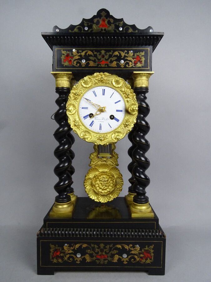 Null 一个发黑的木质门廊钟，装饰有玳瑁、珍珠母和黄铜镶嵌物，放在四个扭曲的柱子上。珐琅表盘上标有 "Gorini Frères à Paris"，并有罗马数&hellip;
