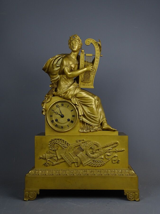 Null 鎏金铜钟，装饰着一个拿着琴的音乐家，底座有音乐属性。带有罗马数字的表盘。19世纪上半叶。尺寸：50 x 34 x 14厘米。有了它的钥匙。