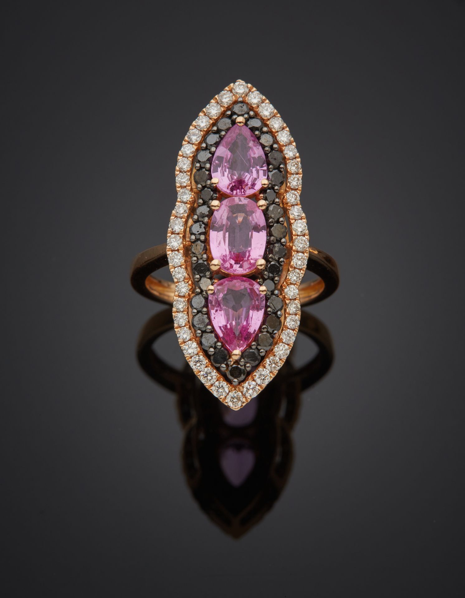 Null 重要的镂空粉红和熏黑金（750‰）"榄尖形 "戒指，镶有三颗梨形和椭圆形粉红蓝宝石，周围有白色和黑色明亮式切割钻石。
蓝宝石的重量：2.5克拉左右。
&hellip;