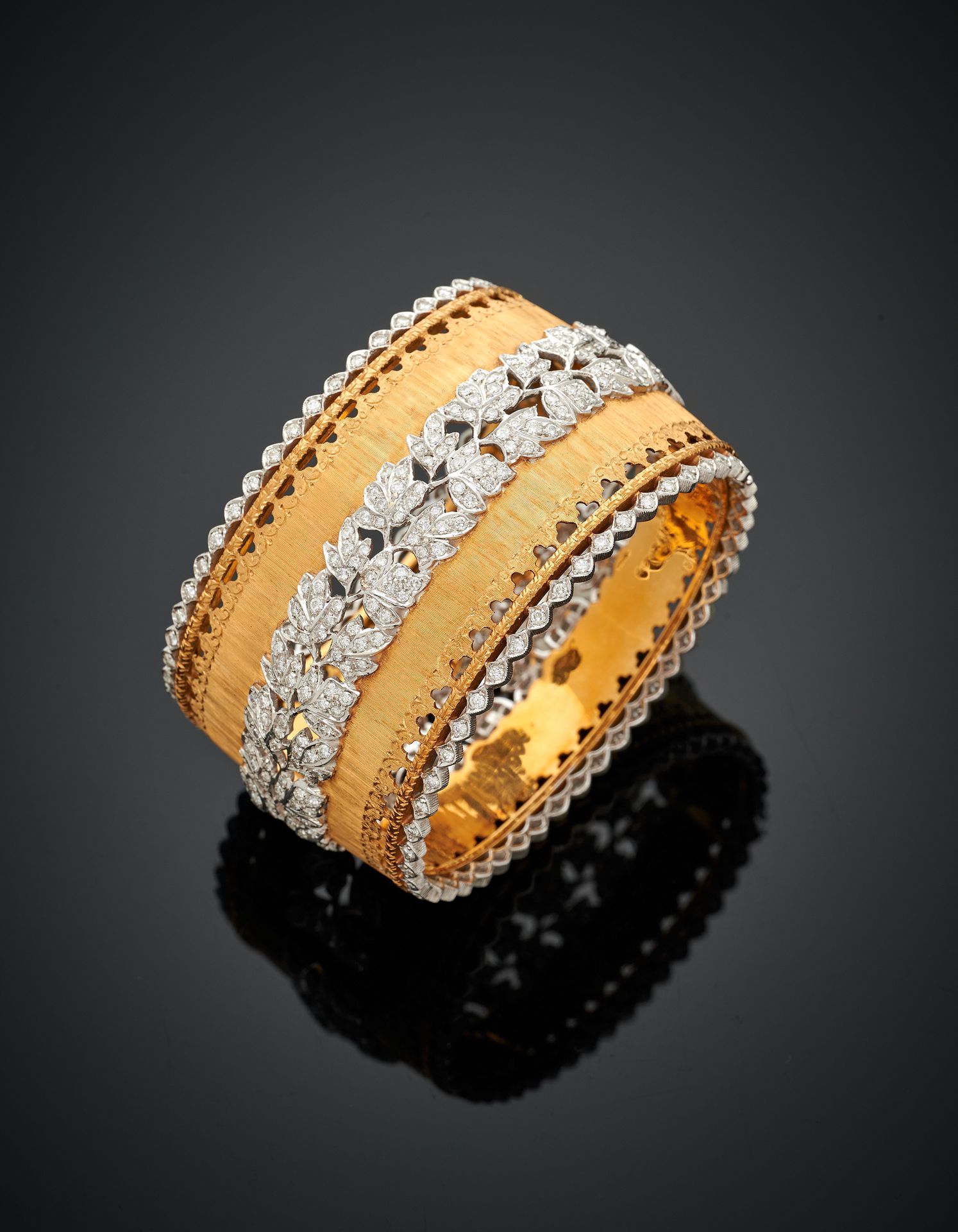 Null 重要的大型黄金和白金（750‰）"袖口 "手镯，非常精细的玑镂、镂空和重塑，中心是铺满钻石的叶子楣，边上是明亮式切割钻石的排列。
意大利作品。 
长度&hellip;