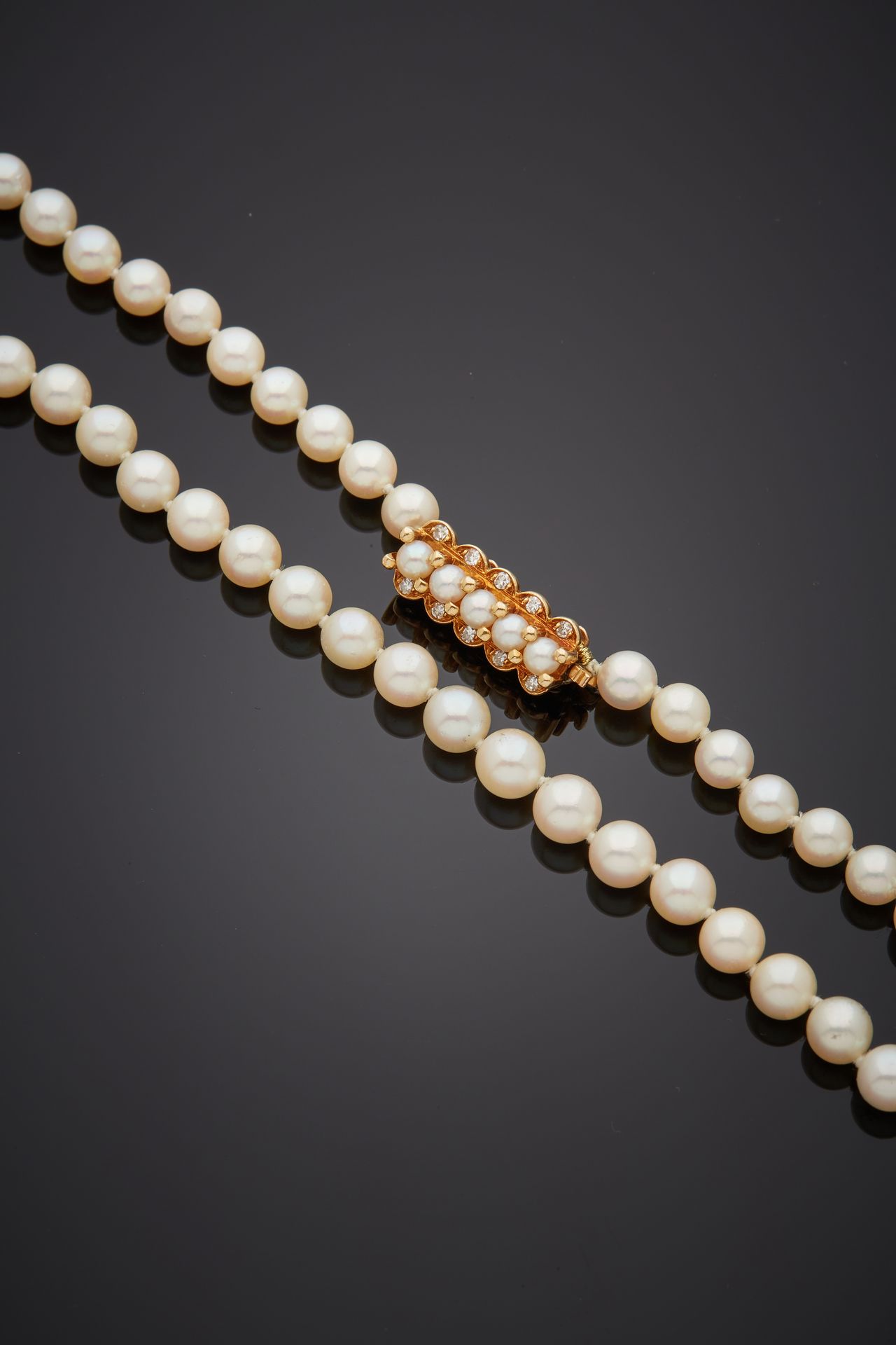 Null 项链由一排白色养殖珍珠组成。黄金（750‰）"发夹 "扣（原为手镯，重新穿线）上装饰有五颗养殖珍珠，并镶有8/8切割钻石。 
珍珠的直径：5.5至6.&hellip;