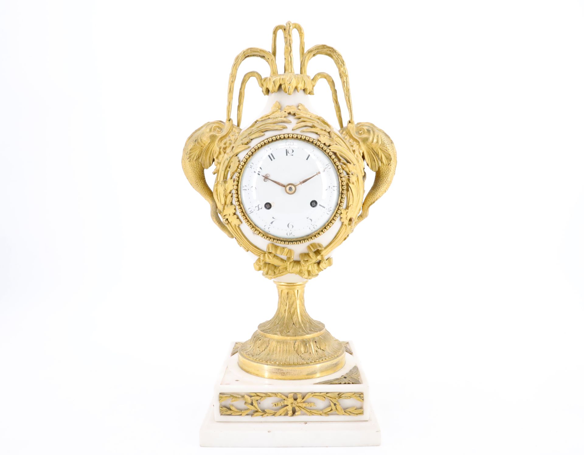 Null 一个路易十六时期的花瓶钟 "aux dauphins"，由白色大理石和带凹槽的鎏金青铜制成，白色珐琅的表盘上刻有阿拉伯数字，表圈上有一排珍珠，表壳由橡&hellip;