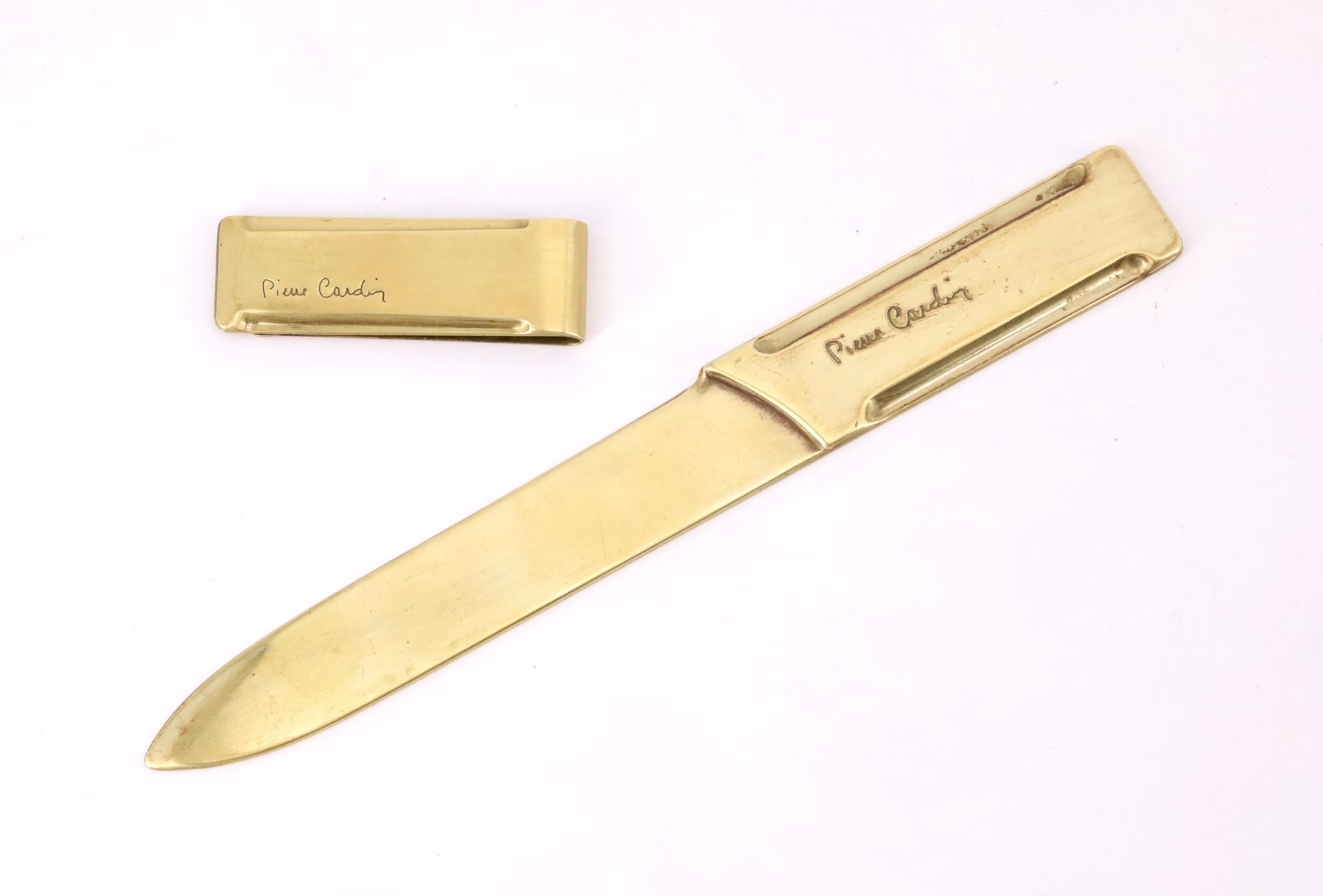 Null 皮埃尔-卡丹（1922-2020），铜质纸刀和钱夹，已签名（使用后有划痕）--长19厘米（纸刀）；长6厘米（钱夹）。
