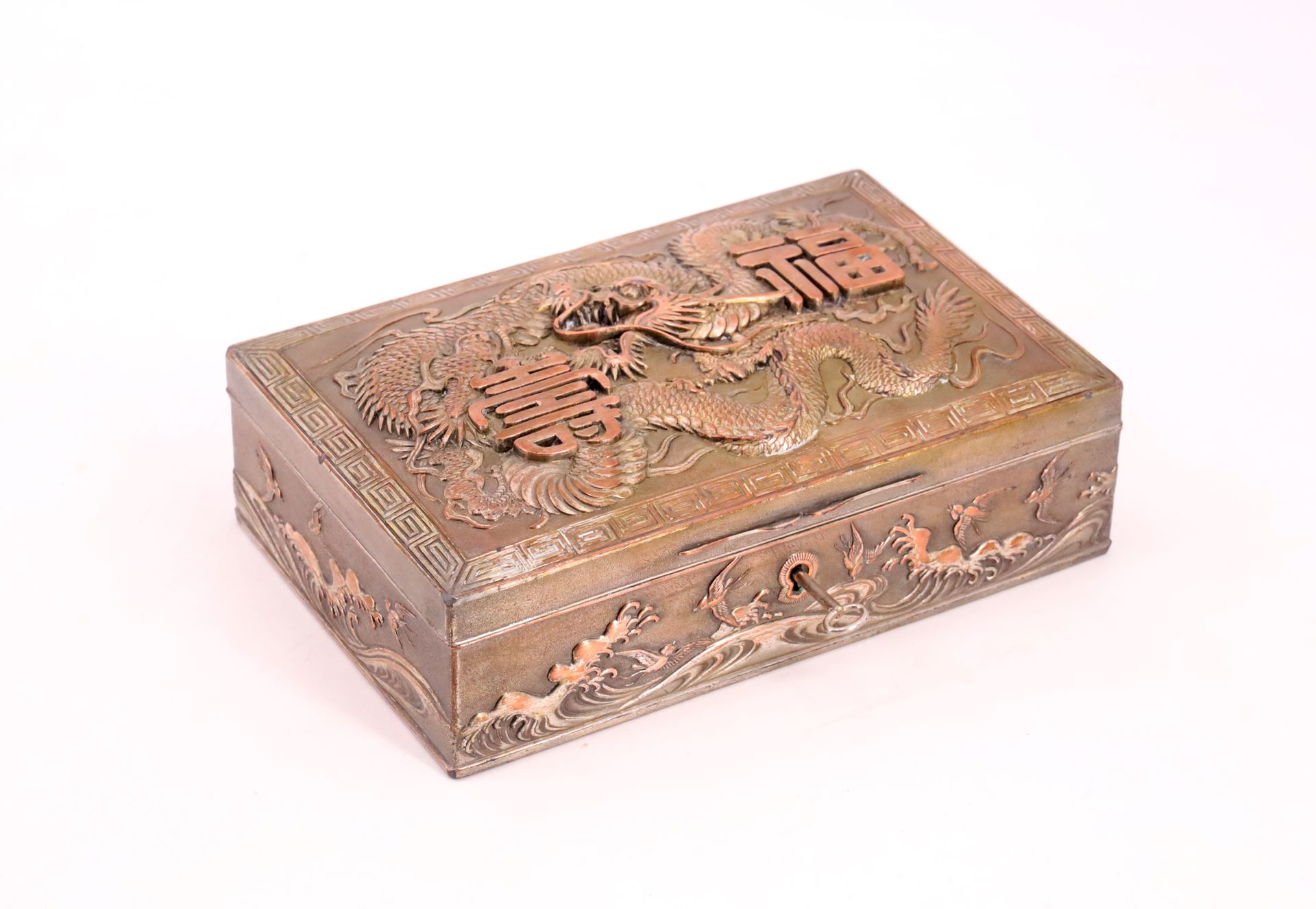 Null 长方形的镀银铜珠宝盒，盒盖上的浮雕装饰是一条龙和希腊人物框架中的表意文字，侧面是波浪之上的鸟儿 - 印度支那，20世纪初 - 高6厘米，宽21厘米，深&hellip;