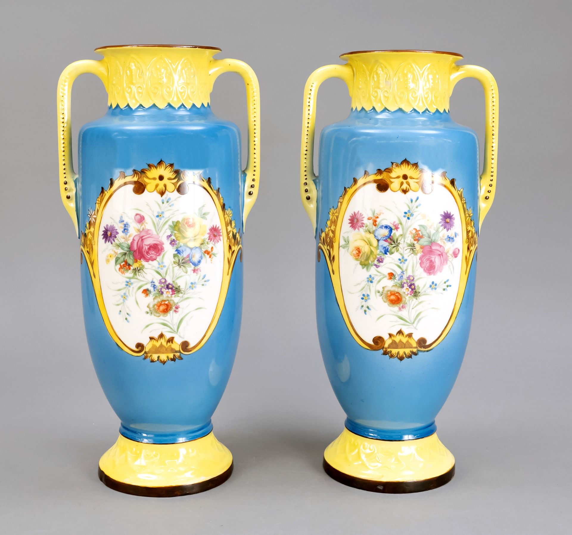 Null 一对大型陶瓷花瓶，20世纪上半叶，圆形支架，瓮形瓶身，侧面有把手，蓝色和黄色的背景，多色花装饰在一个装饰的卡图上，高40,5厘米