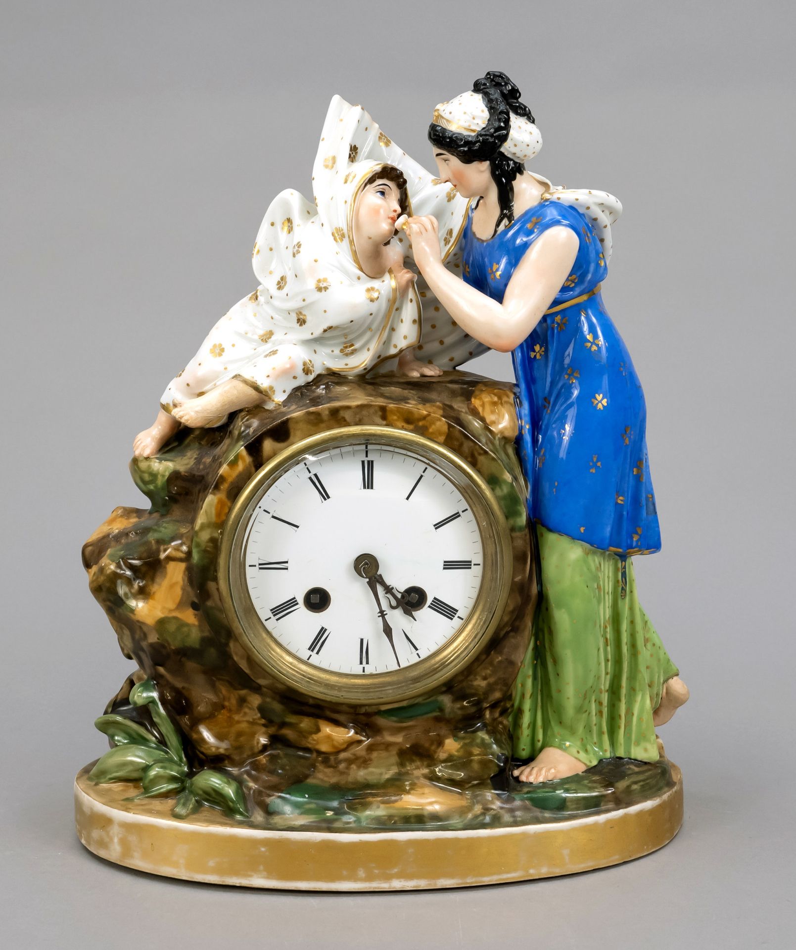 Null 一个具象的壁炉钟，法国，19世纪，圆形玻璃罩后面的珐琅表盘上有罗马数字，机芯上有铃铛，镶嵌在一个岩石形状的瓷盒里，还有两个人物，一个母亲在喂她的孩子，&hellip;