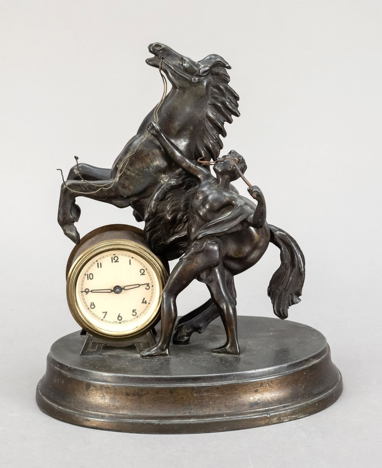 Null 桌钟，白色铸铁，20世纪上半叶，男人抱着一匹正在奔跑的马，在椭圆形的底座上，镀金的钟鼓里的针杆机芯开始，高23厘米，宽18厘米，长13厘米。