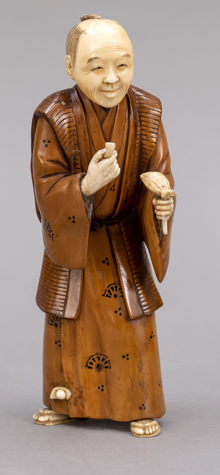 Null 冒烟老人的和服，日本，约1900年（明治）。风格为克莱斯勒象派人物：浅色根木的长袍，部分上色。象牙的头、手和脚。脚间有嵌红漆板上的签名，高15厘米。