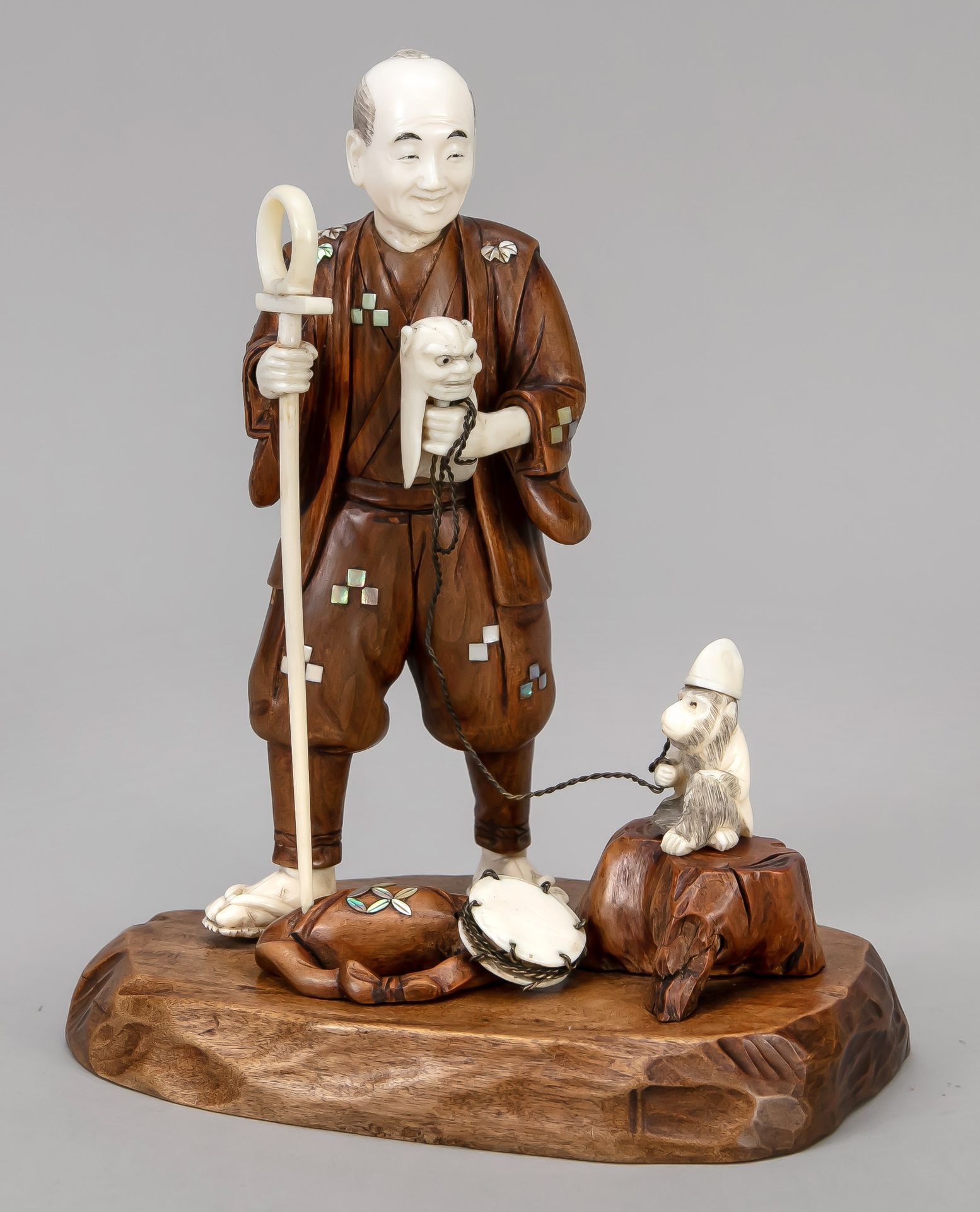 Null Okimono，日本，20世纪初，象牙/木材。带着链子上的猴子和手偶的表演者。底座下有一个嵌有象牙的刻线的签名，22 x 18 x 13厘米。