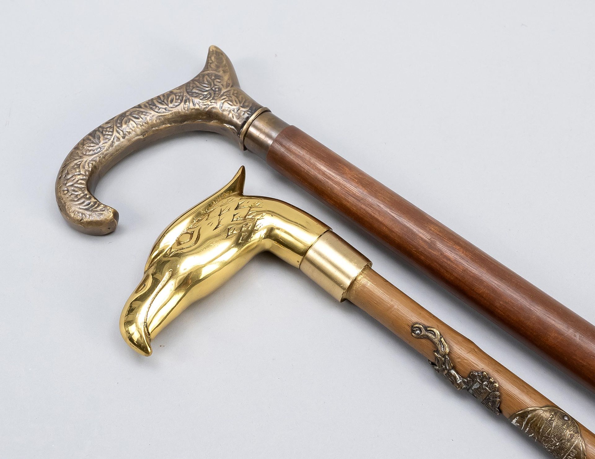 Null 2根手杖，20世纪，1根有鹰头鞍座，1根鞍座装饰有叶子和胡桃木轴，都是黄铜的，高达92厘米。
