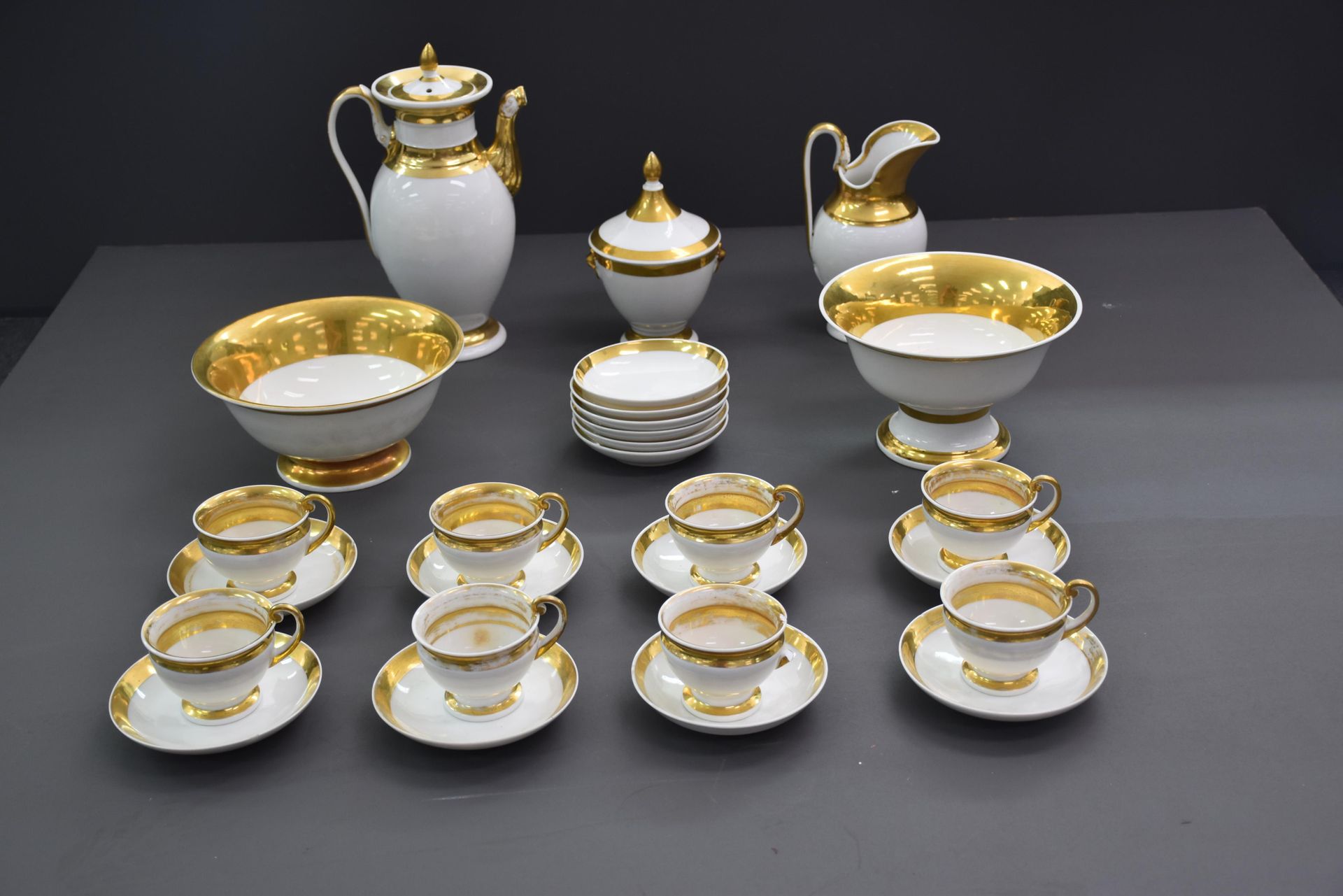 Null 布鲁塞尔瓷器的咖啡服务的一部分，有金色的边缘。帝国风格。由一个咖啡壶，一个牛奶壶，八个杯子和碟子以及两个糖果碗组成。一些事故。(指板背面胶合，手柄背面&hellip;