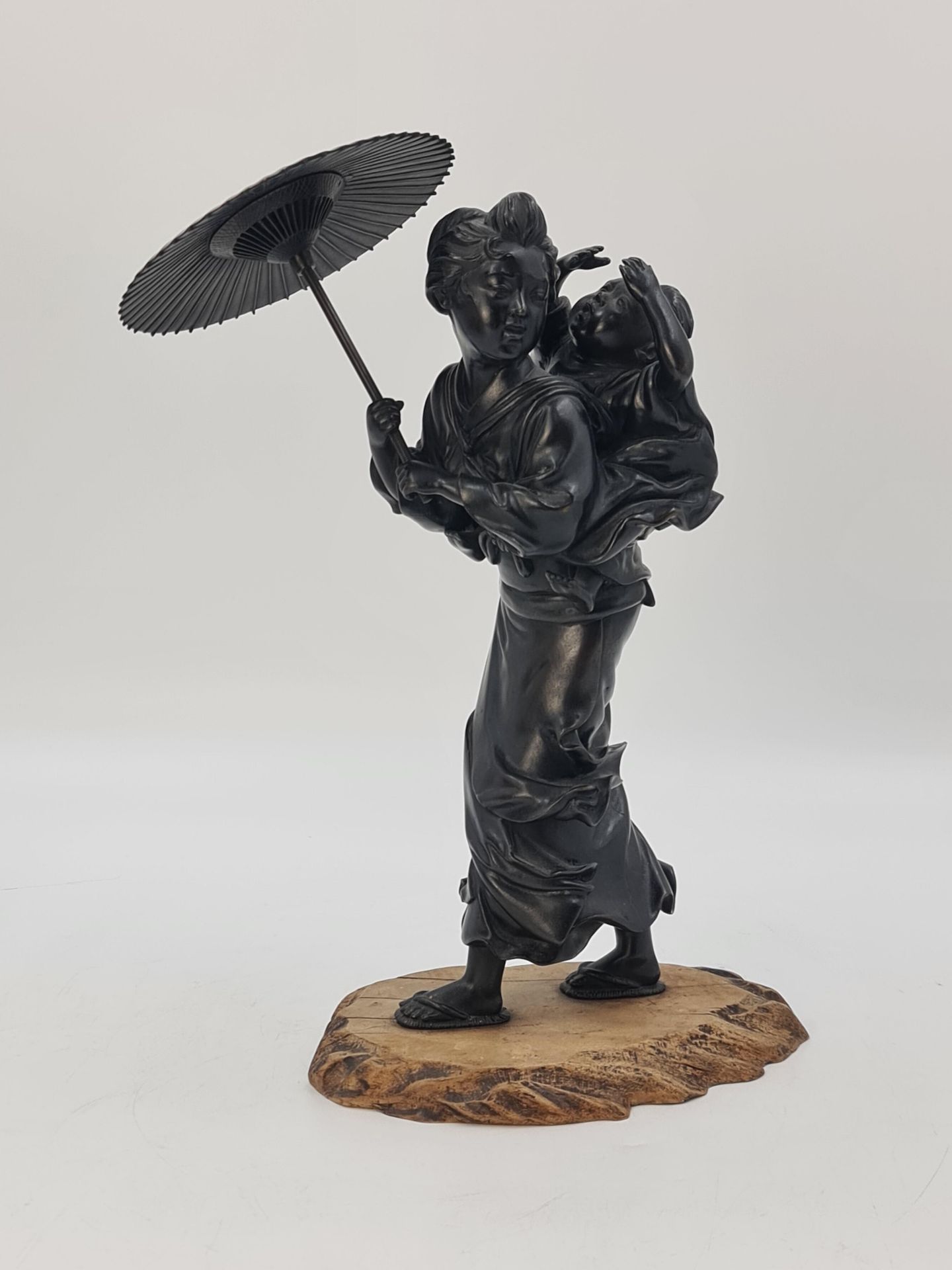 Null 棕色铜质和服，表现一位年轻女子在风中行走，她手中的阳伞，头转向她背上的孩子。日本，明治时期，（1868-1912）。高度：35厘米。

古铜色的和服，&hellip;