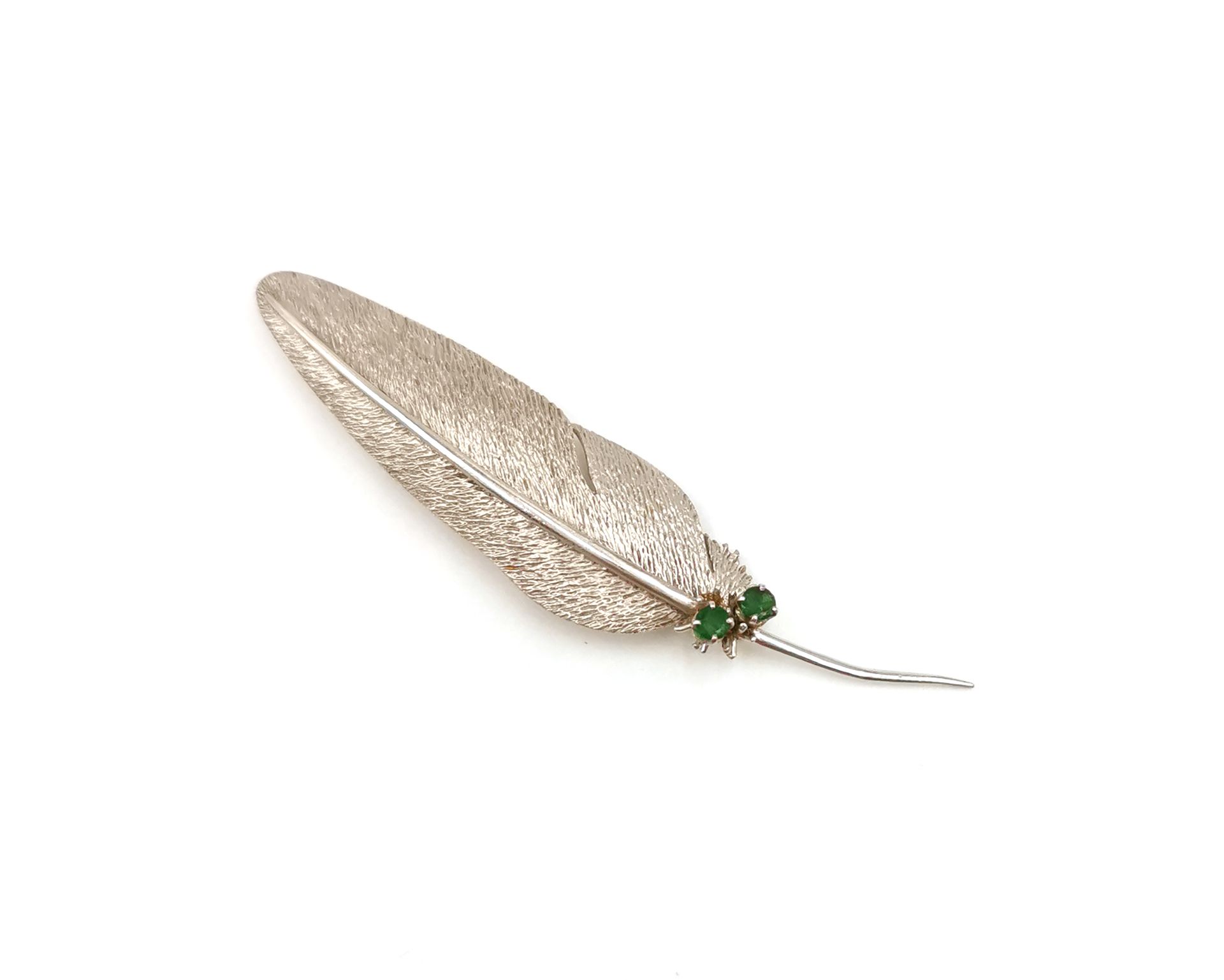 Null 18K（750千分之一）白金胸针，羽毛设计，镶嵌两颗绿色宝石

长度： 8 cm

毛重：10,1克。