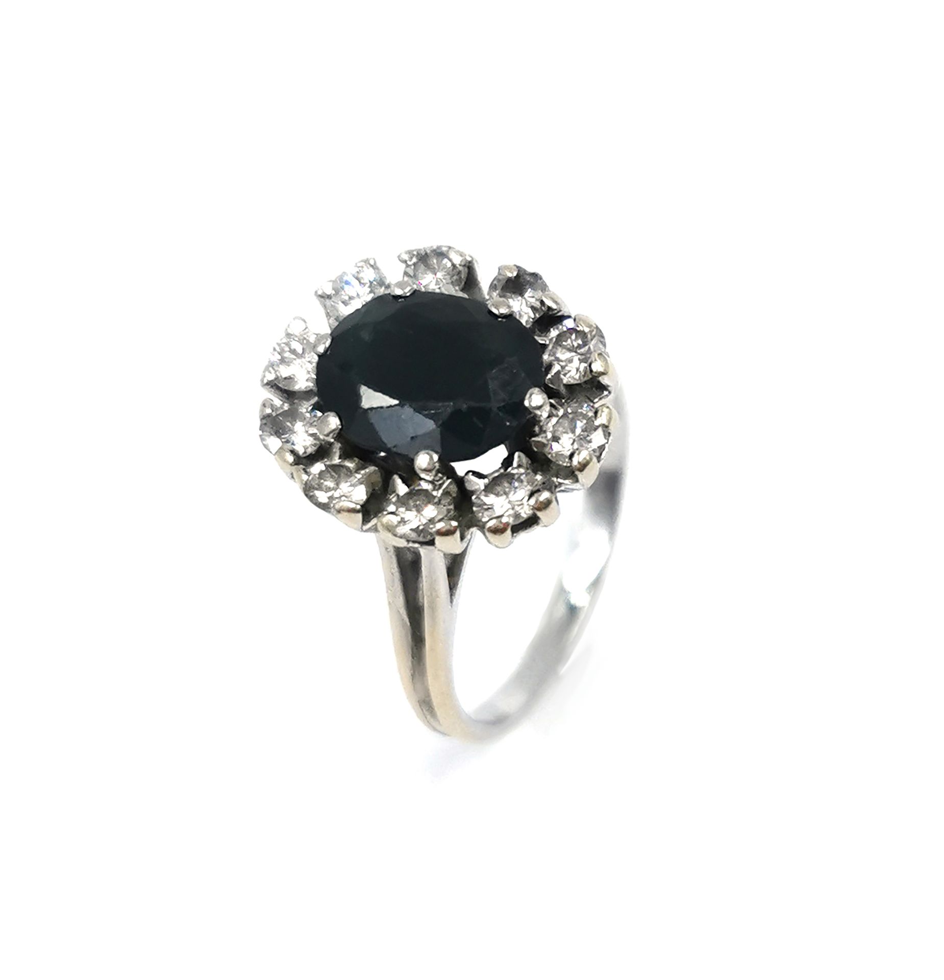 Null 18K（750千分之一）白金戒指，镶有一颗椭圆形刻面蓝宝石（有些碎片），并镶嵌有十颗圆形明亮型钻石

手指大小：53

毛重：5.8克。