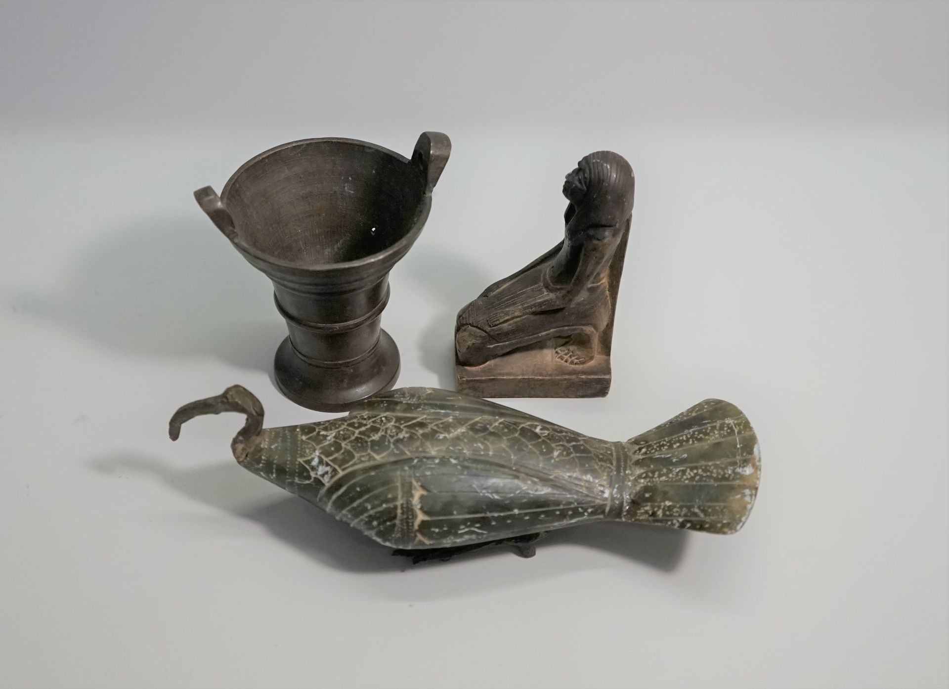 Null 一套三件物品，包括一个金属和复合材料的躺着的朱鹮，一个微型铜臼和铁杵，以及一个埃及风格的跪着的人物。

9.5厘米、9.5厘米和19厘米