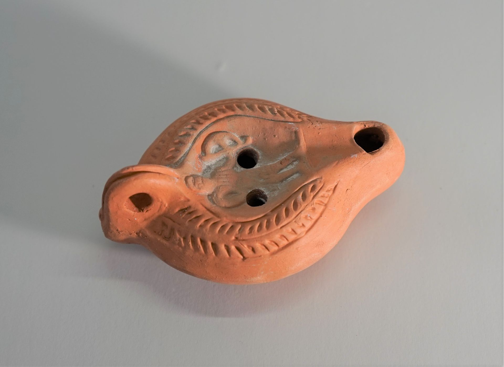 Null Orange terracotta oil lamp, decorated with an archer, Roman style. 

11.5cm