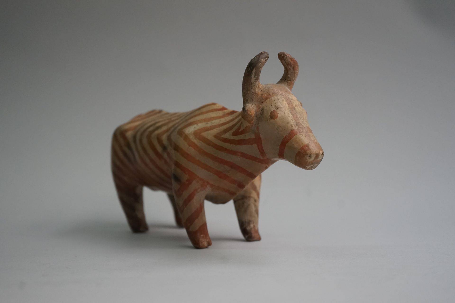 Null 一头橙色和米色的赤土牛，有人字形线条图案。

公元前3千年的风格，土耳其。

14x24厘米