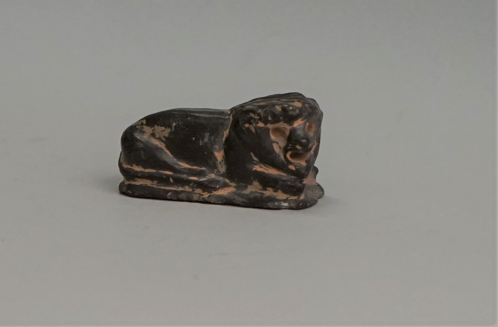 Null Lion couché en pierre tendre noire, Proche Orient. 5.7x3cm