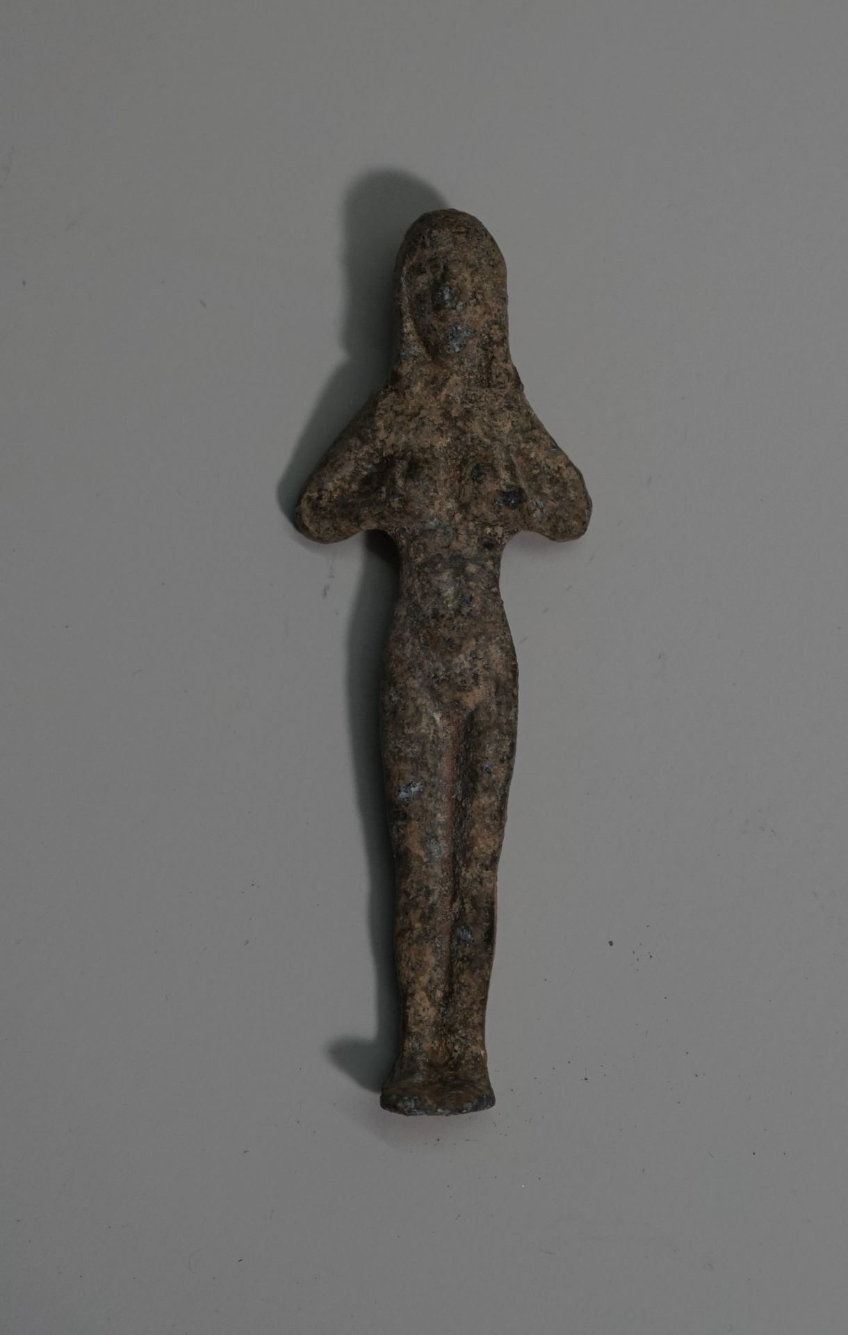Null 镀锡铁合金的小型女性偶像，双手放在胸前。晚期腓尼基托勒密风格。高：8.2厘米