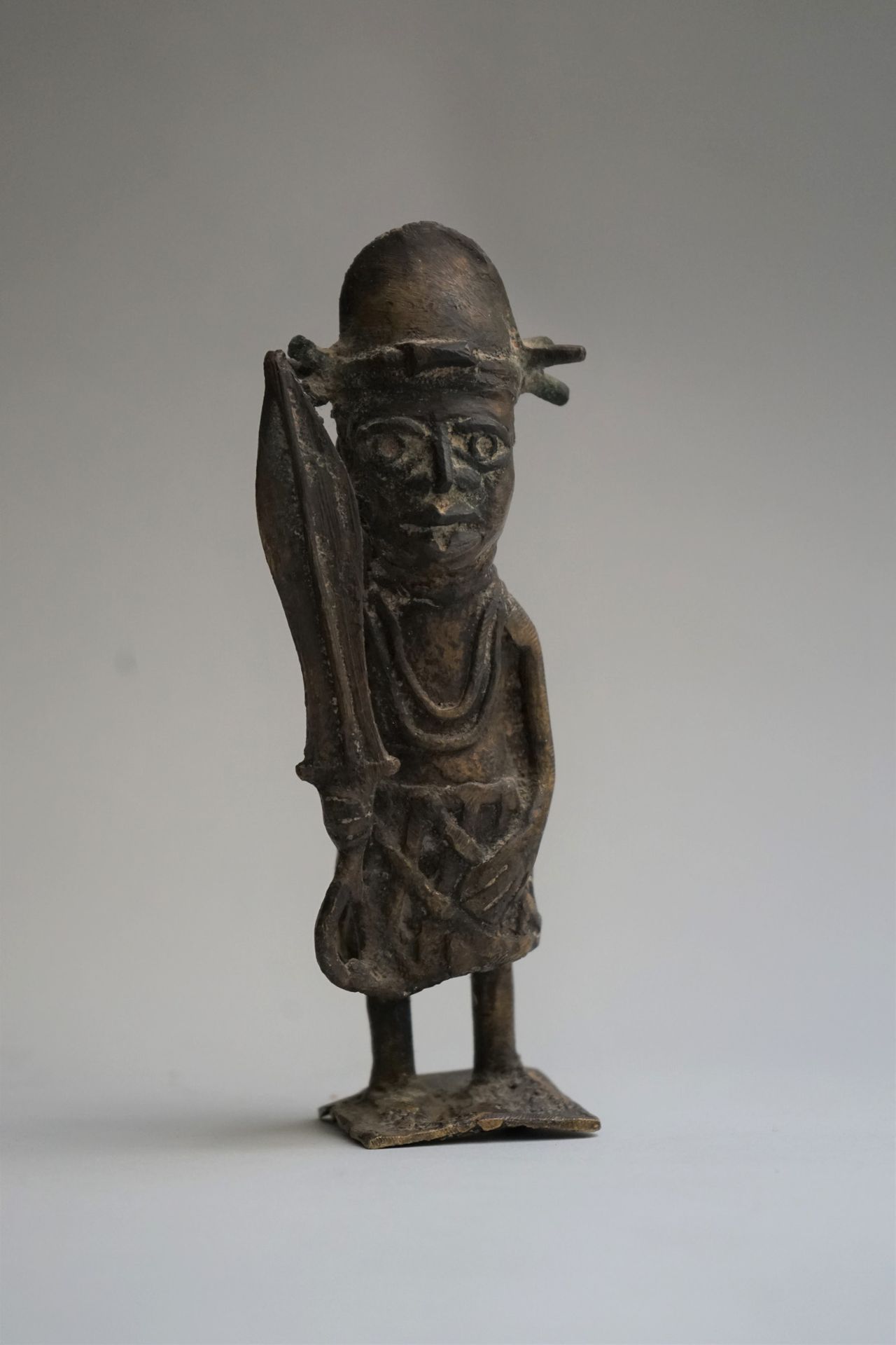Null 雕像展示了一个手持剑、头戴头盔的士兵。青铜，带有棕色的铜锈。

中部非洲。

高：16.5厘米