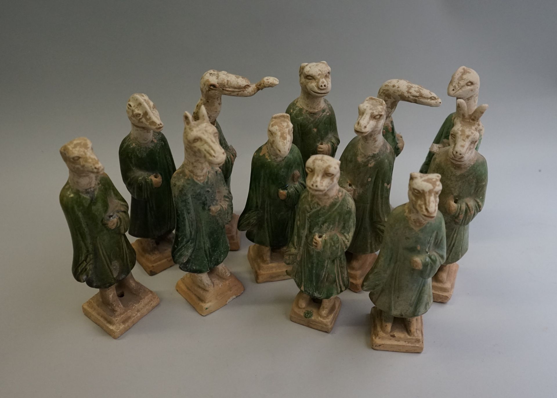 Null 12个带十二生肖头像的游行队伍，米白色陶器，绿色釉面。

明，公元1368-1644年，中国。

高：从19.5厘米到21.8厘米。

所有的头都被报&hellip;