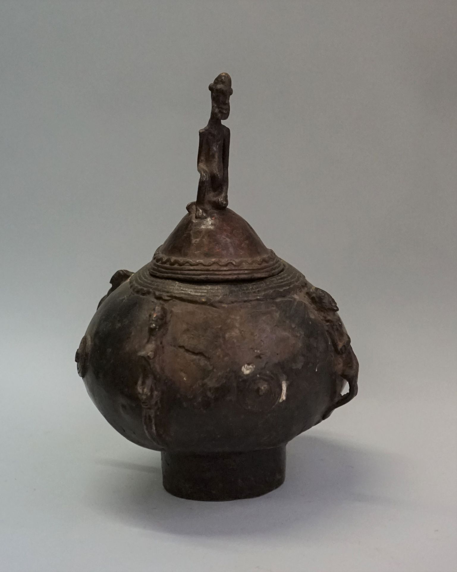 Null 一个带盖的青铜花瓶，有旧的和使用过的铜锈，装饰着四个象征性的女性和男性形象。盖子上装饰着一个跪着的大胡子男性形象。

多贡，马里。

深：14厘米，高&hellip;