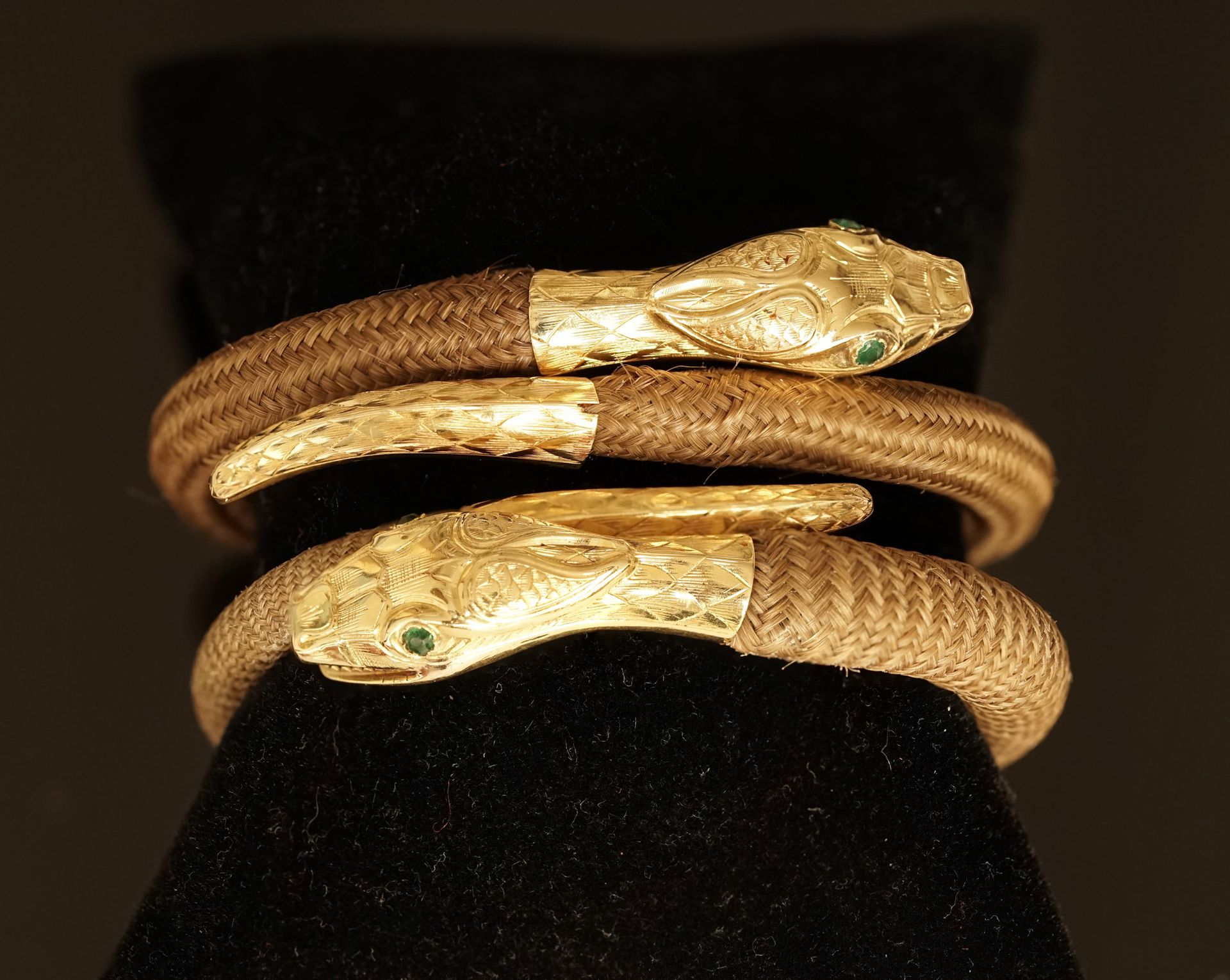 Null 一对18K（750/°）黄金手镯，以蛇头和蛇尾为特色，眼睛镶嵌着绿宝石，蛇身由美丽的发辫组成。法国作品，19世纪中期。内部直径：5.3厘米，PB：18&hellip;