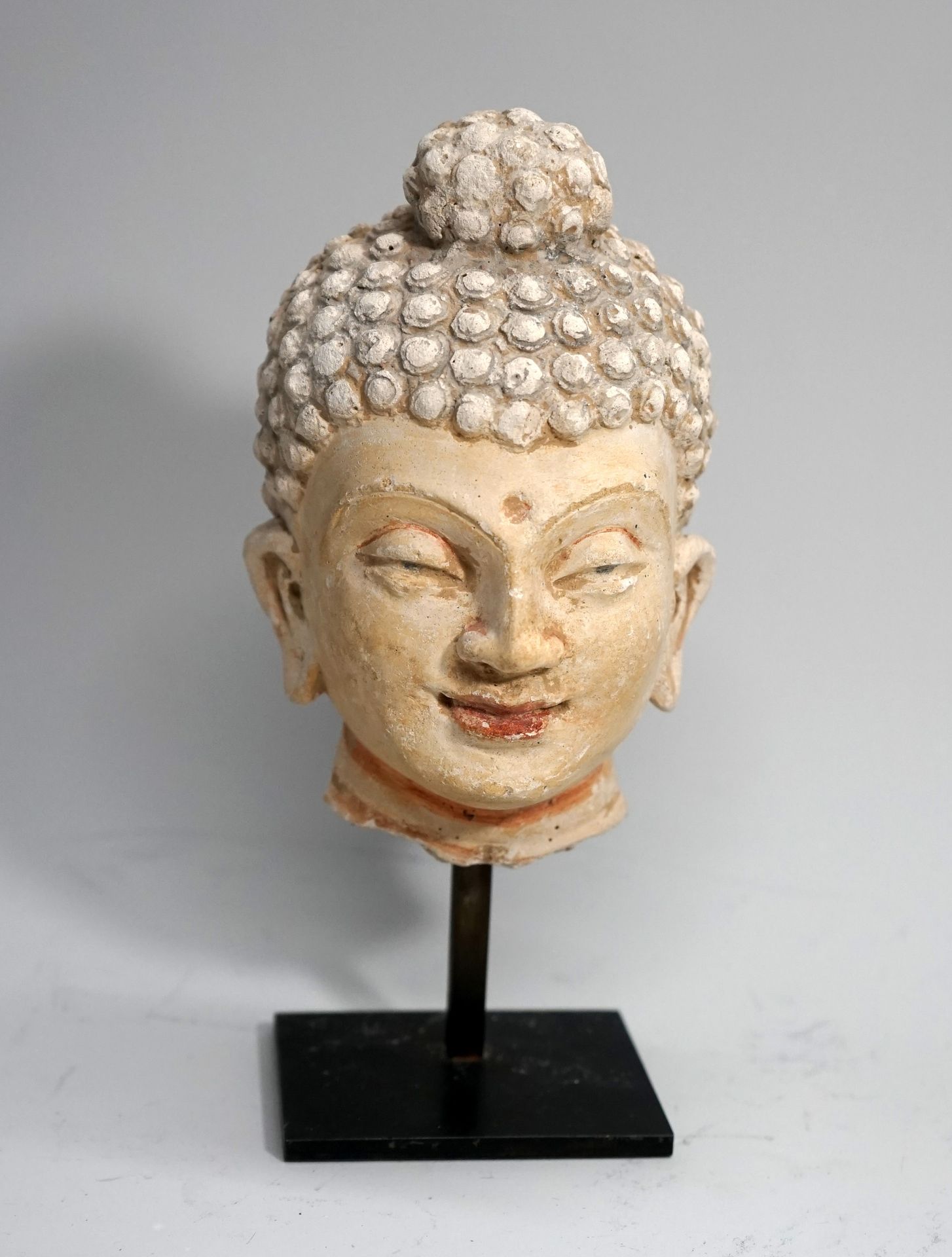 Null 多色灰泥的佛祖头像，他戴着一个带有中央千手观音的头饰。修复和多色重做。犍陀罗的希腊佛教艺术。15厘米。基座。
