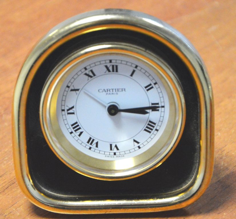 CARTIER 时钟 - MUST 闹钟，镀金金属材质，带可伸缩底脚，刻有卡地亚 "C "字样，罗马数字显示小时，黑色漆框。 
机械机芯（发条手柄已损坏）。
7&hellip;