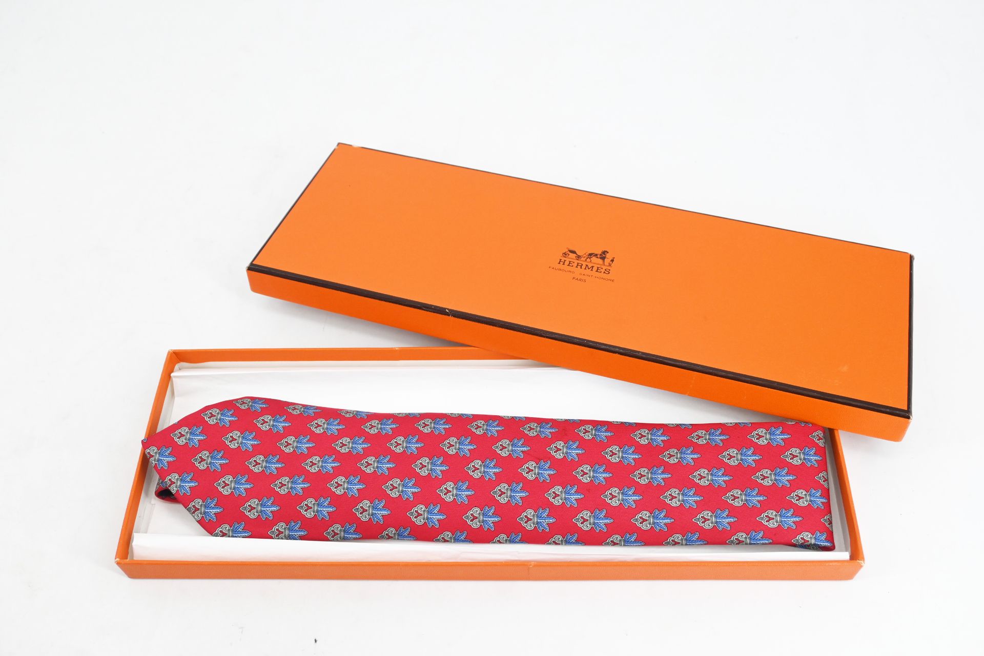 Null 爱马仕 -
丝质领带，红底蓝羽毛花束装饰（有轻微污渍）及其包装盒（有冲击）。