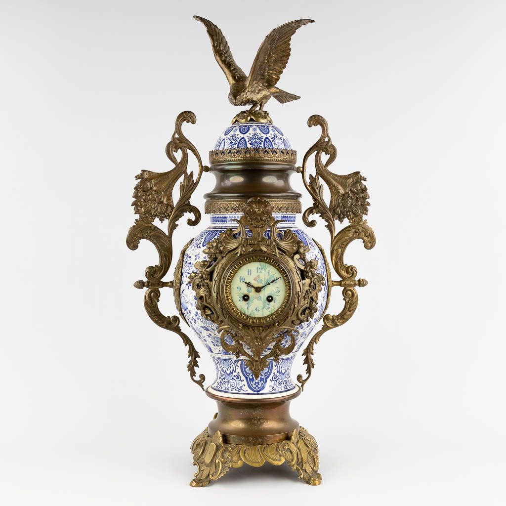 Null 
A mantle clock, Delfts faience mounted with bronze and an eagle figurine. &hellip;