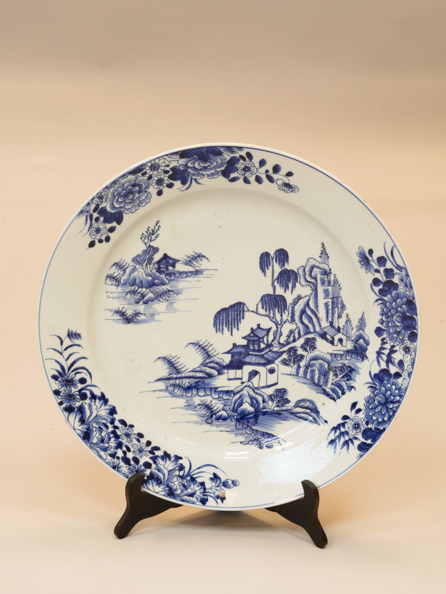 Null 
中国，19世纪，用于出口。圆形盘子，中间装饰有湖泊景观。边缘上有一束花。白色和蓝色的釉面瓷器。直 径：41.5厘米。
边界和脚上有缺口。