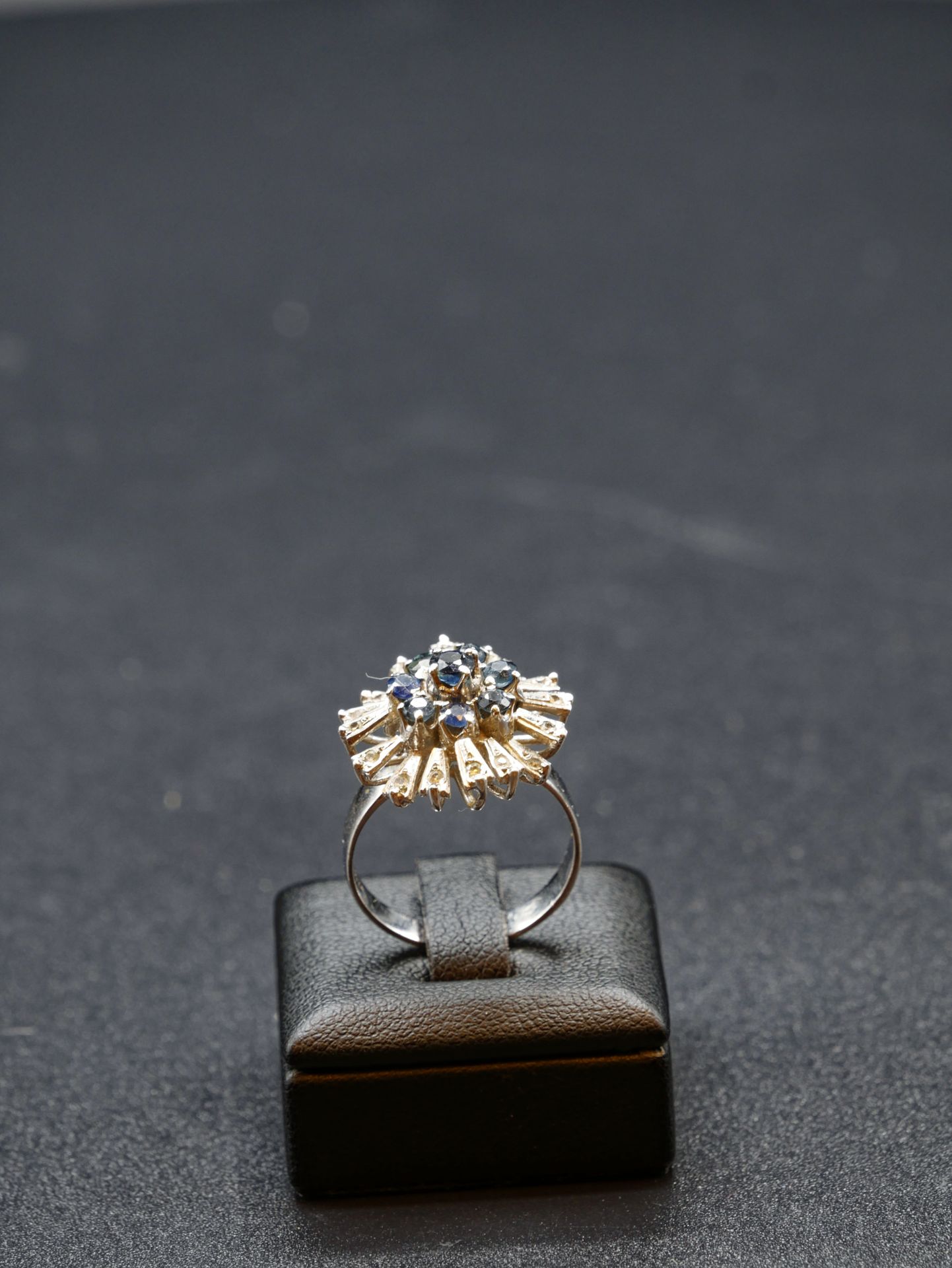 Null 
Un anello d'argento a forma di fiore con otto pietre blu e sedici diamanti&hellip;