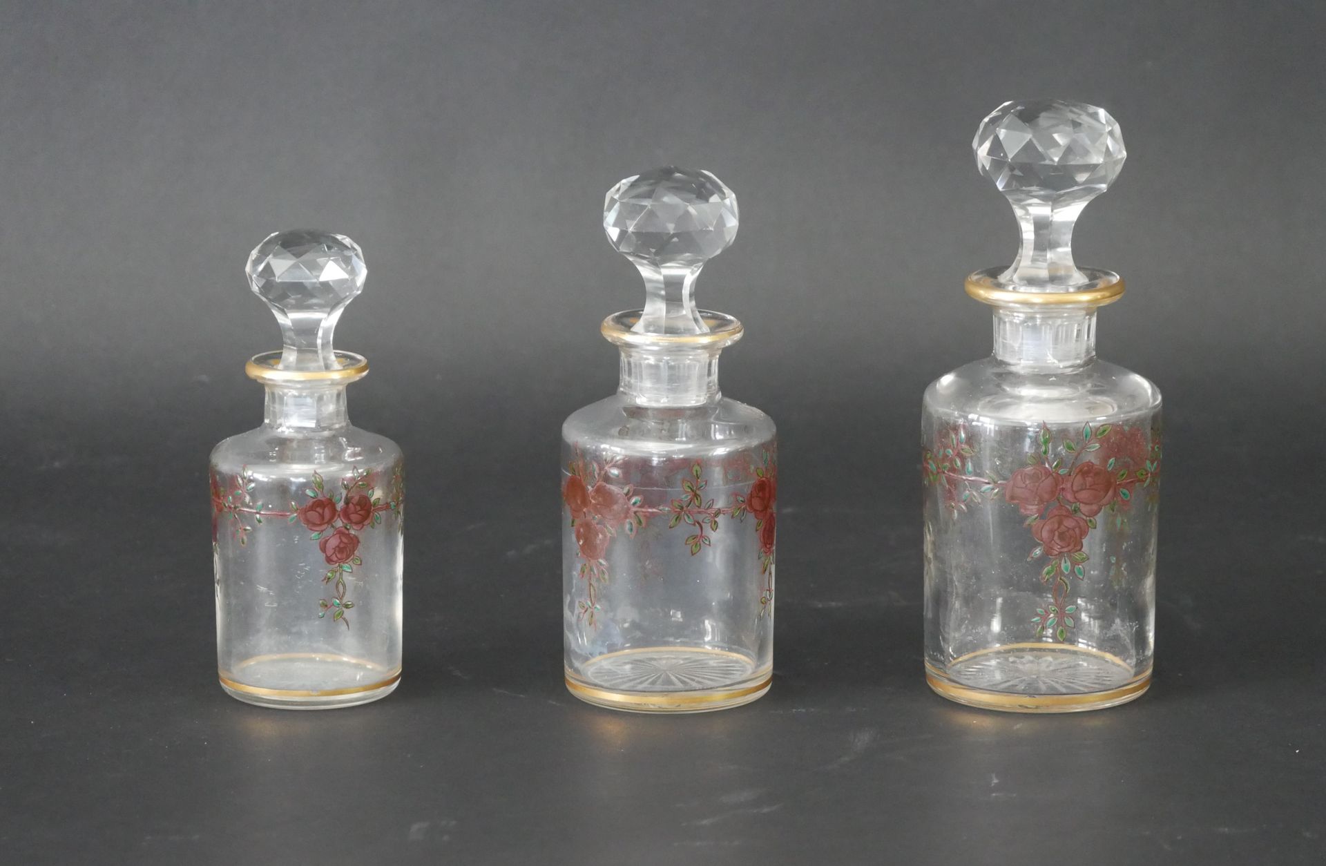 Null 一套三件玻璃瓶，有彩绘花纹和瓶塞（其中一个瓶塞损坏）。高度：14厘米、16厘米和18厘米。