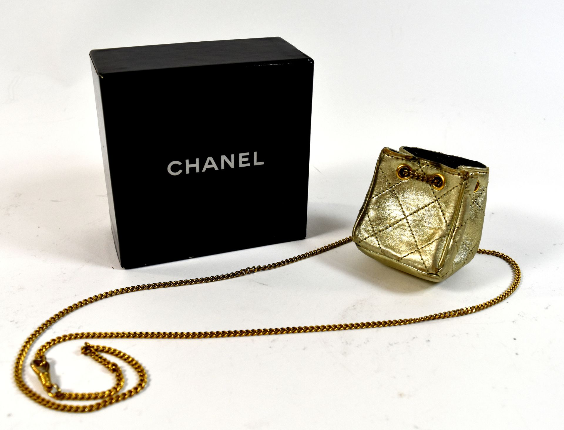 Null 镀金项链配以署名为 "香奈儿 "的镀金钱包（略有损坏）+原包装盒

NL :

 在褶皱中的半身裙，带有香奈儿的小标签（有瑕疵）+原件。