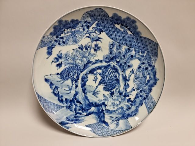 Null 日本，19世纪。一个青花瓷盘，上面装饰着鸟、石头和丝带。直径：30厘米。背面的标记（fele）